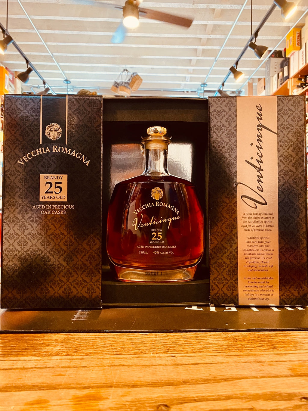 Vecchia Romagna 25yr 750mL an open black and golden box with a flat surfaced short round shouldered clear glass bottle inside with a golden top