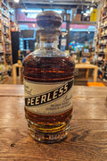Peerless Bourbon Rum Barrel Finished 750mL a short squat rounded clear glass bottle with a beige and green label with a wooden top