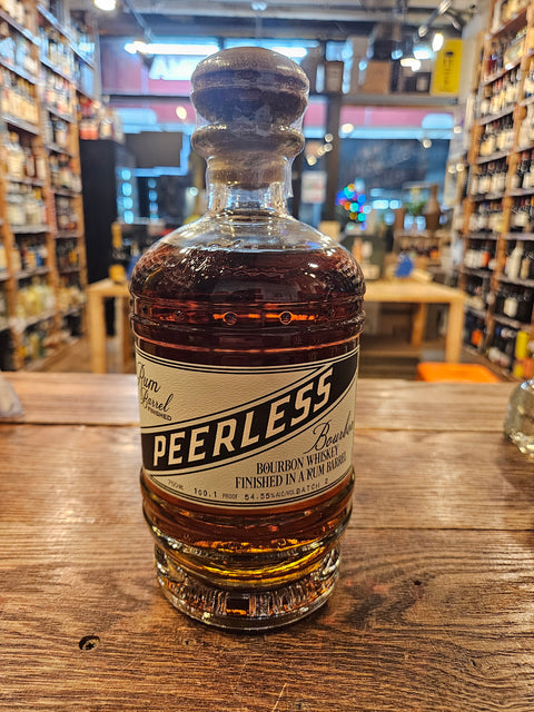 Peerless Bourbon Rum Barrel Finished 750mL a short squat rounded clear glass bottle with a beige and green label with a wooden top