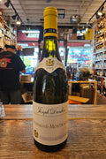 Wine bottle on a wooden surface with a blurred store interior in the background