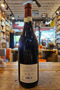 Wine bottle with a label on a wooden surface, with a store interior in the background