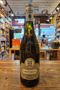 Bottle of Pinot Grigio on a wooden surface with a store interior in the background