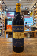 Bottle of Solengo wine on a wooden surface with a store interior in the background