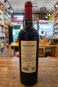 Bottle of wine with a label on a wooden surface, blurred store interior in the background