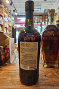 Bottle of Amaro Imperiale on a wooden surface with a blurred store interior in the background