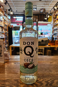 Bottle of Don Q coconut rum on a wooden surface with a blurred bar background