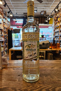 Bottle of Stoli Vanilla vodka on a wooden surface with a blurred indoor background