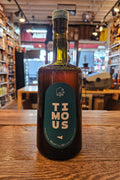 Bottle of Timous Amaro on a wooden surface with a blurred bar background