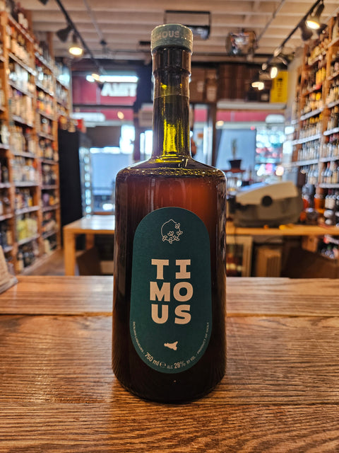 Bottle of Timous Amaro on a wooden surface with a blurred bar background