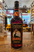 Bottle of Goslings Black Seal Bermuda Black Rum on a wooden surface with a blurred store interior in the background.