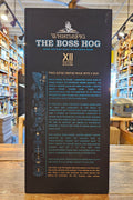 WhistlePig The Boss Hog XII whiskey bottle label on a wooden surface with a blurred store background.