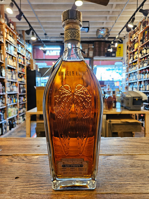 Bottle of Angels Envy 10 year on a wooden surface with a store interior in the background