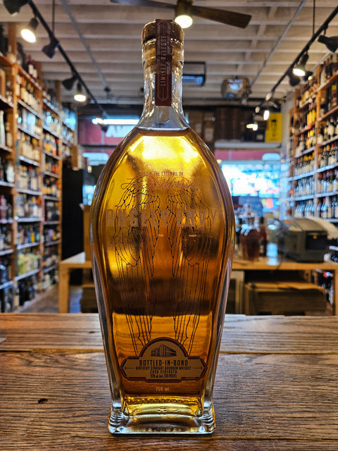 Bottle of Angels Envy Cask Strength Bottled in Bond on a wooden surface with a blurred store interior in the background