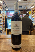 Bottle of Duca Enrico wine on a wooden surface with a blurred store interior in the background