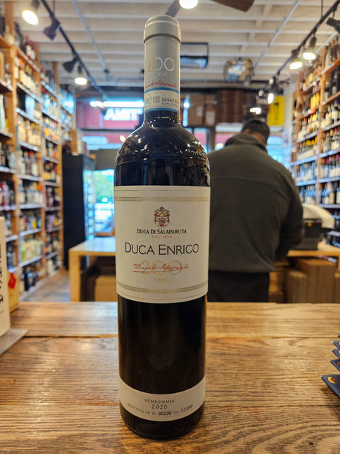 Bottle of Duca Enrico wine on a wooden surface with a blurred store interior in the background