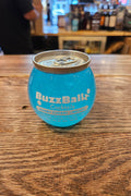 Blue BuzzBallz cocktail can on a wooden surface with a blurred bar background