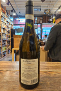 Bottle of La Bollina wine on a wooden surface with a store interior in the background