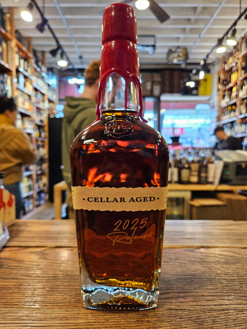 Bottle of 'Cellar Aged' whiskey on a wooden surface with a blurred store interior in the background.