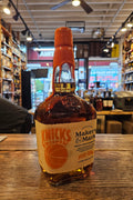Bottle of Maker's Mark bourbon on a wooden surface with a store interior in the background