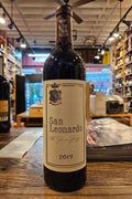 Bottle of San Leonardo wine on a wooden surface with a blurred store interior in the background