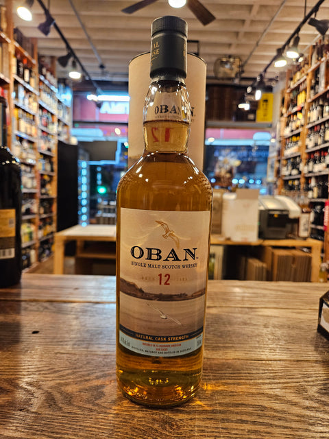 Oban 12-year-old whisky bottle on a wooden surface with a store interior in the background