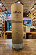 Oban 12-year-old whisky bottle on a wooden surface with a store interior in the background