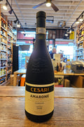 Bottle of Cesare Amarone wine on a wooden surface with a store interior in the background