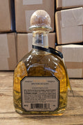 Tequila bottle with a label on a wooden surface with cardboard boxes in the background