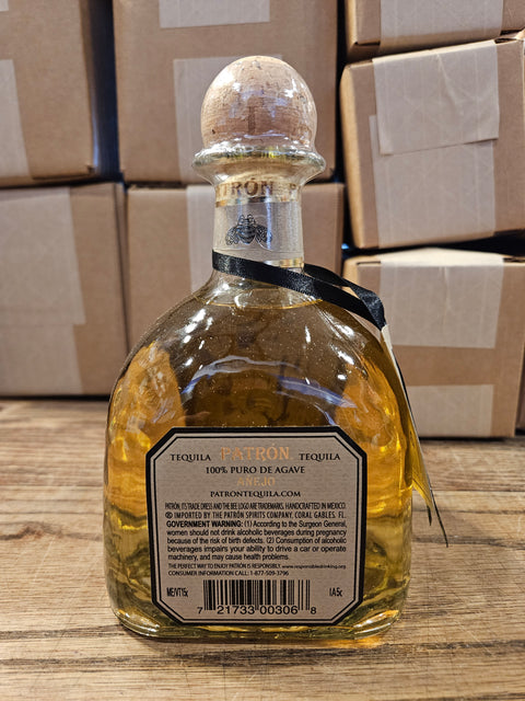 Tequila bottle with a label on a wooden surface with cardboard boxes in the background