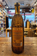 Bottle of Nixta tequila on a wooden surface with a blurred indoor background