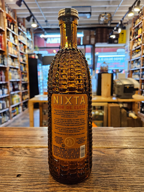 Bottle of Nixta tequila on a wooden surface with a blurred indoor background