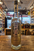 Bottle of G4 Blanco tequila on a wooden surface with a blurred store interior in the background