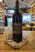 Bottle of Favia wine on a wooden surface with a store interior in the background