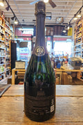 Bottle of champagne on a wooden surface with a store interior in the background
