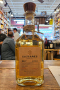 Bottle of Cazcanes tequila on a wooden surface with a blurred indoor background