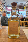 Bottle of Cazqanes tequila on a wooden surface with a store interior in the background