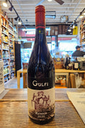 Wine bottle labeled 'Gulfi' on a wooden surface with a blurred indoor background
