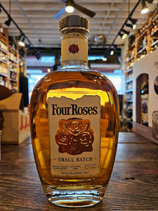 Four Roses Small Batch 750mL a round robust clear bottle with a beige label and four roses engraved on the glass with a wooden top