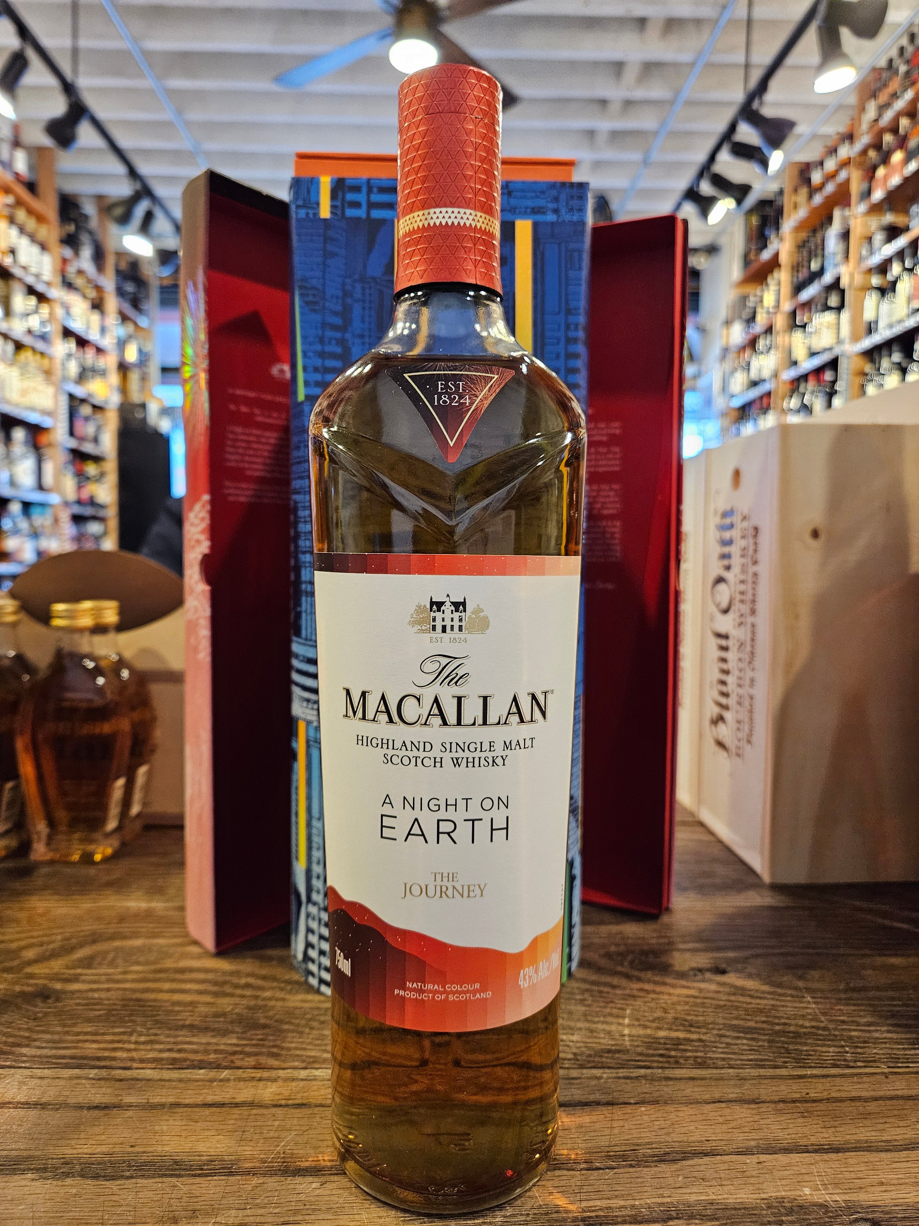 Macallan A Night on Earth - The Journey 750mL a tall clear glass bottle with a white label and orange top