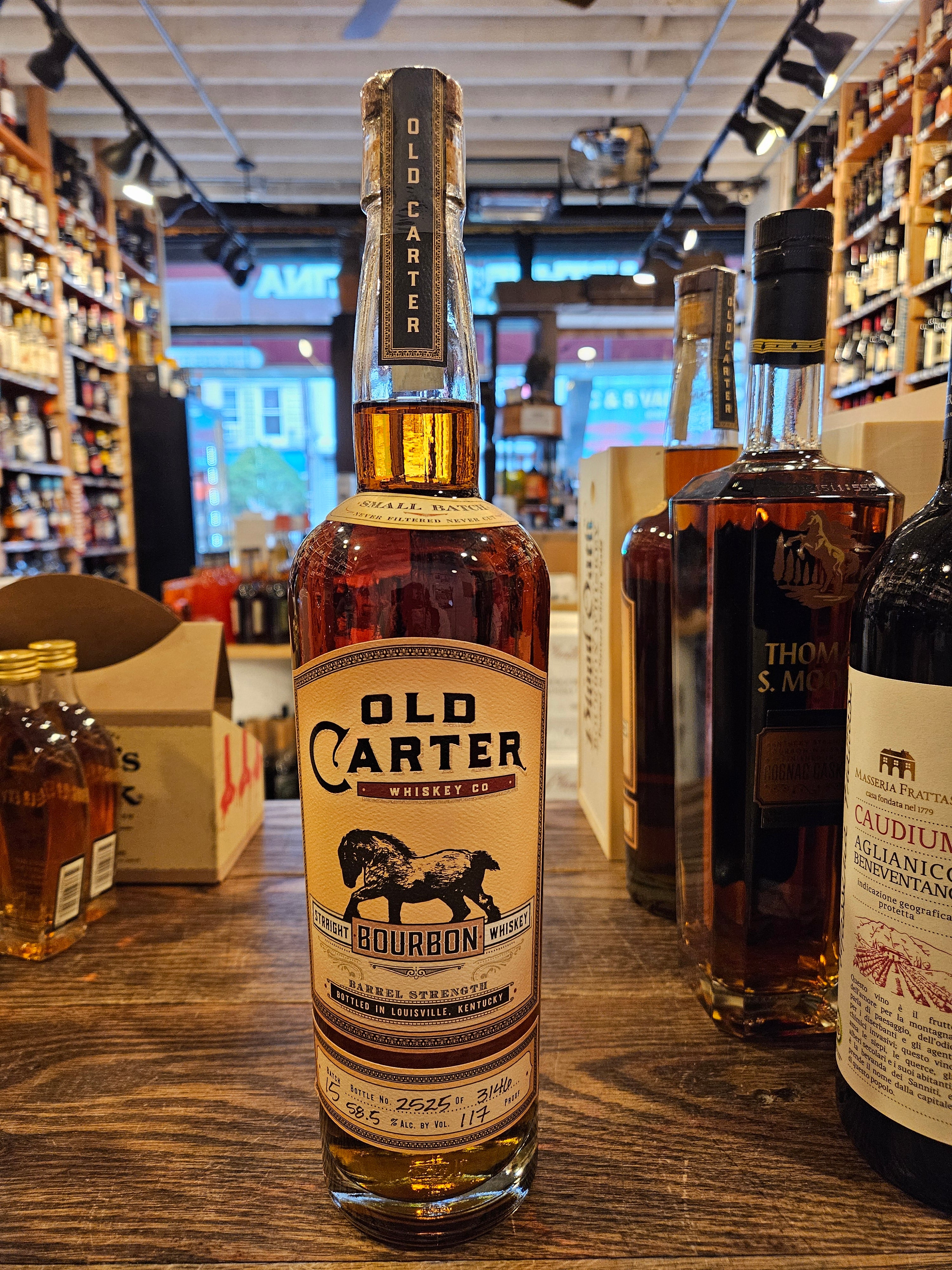 Old Carter Straight Bourbon Whiskey Batch #15 Small Batch  750mL a tall high shouldered clear glass bottle with a beige label and the image of a horse with a wooden top