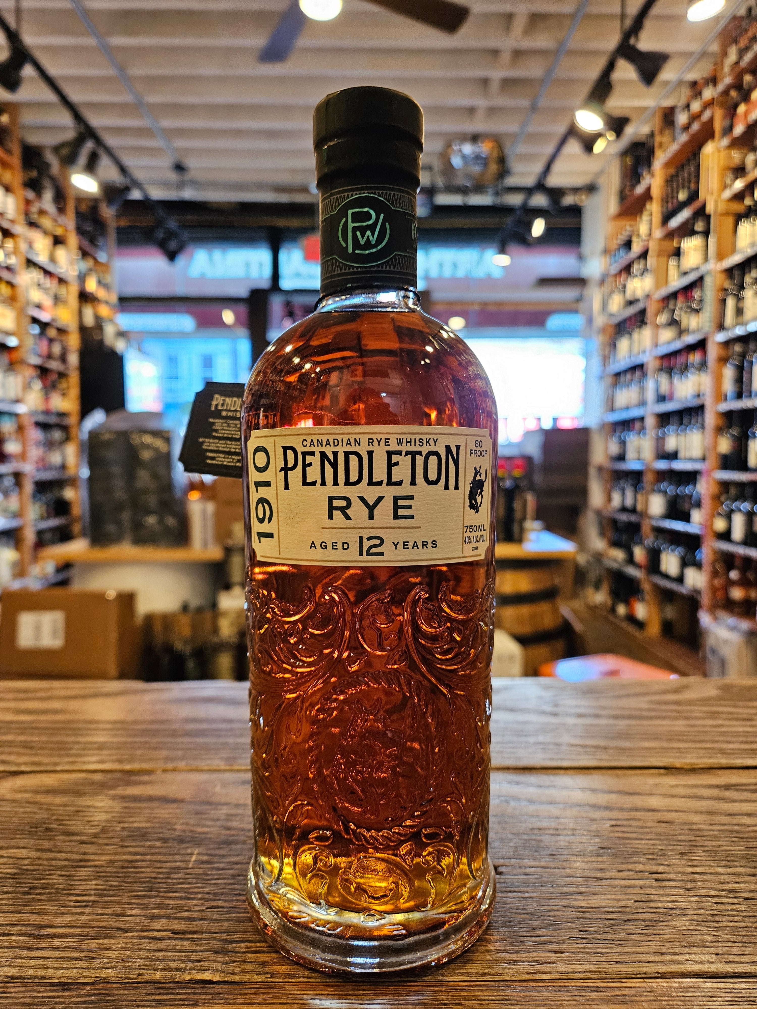 Pendleton 1910 Rye 750mL a high round shouldered clear glass bottle with an intricate design engraved into the glass, a white label and black top