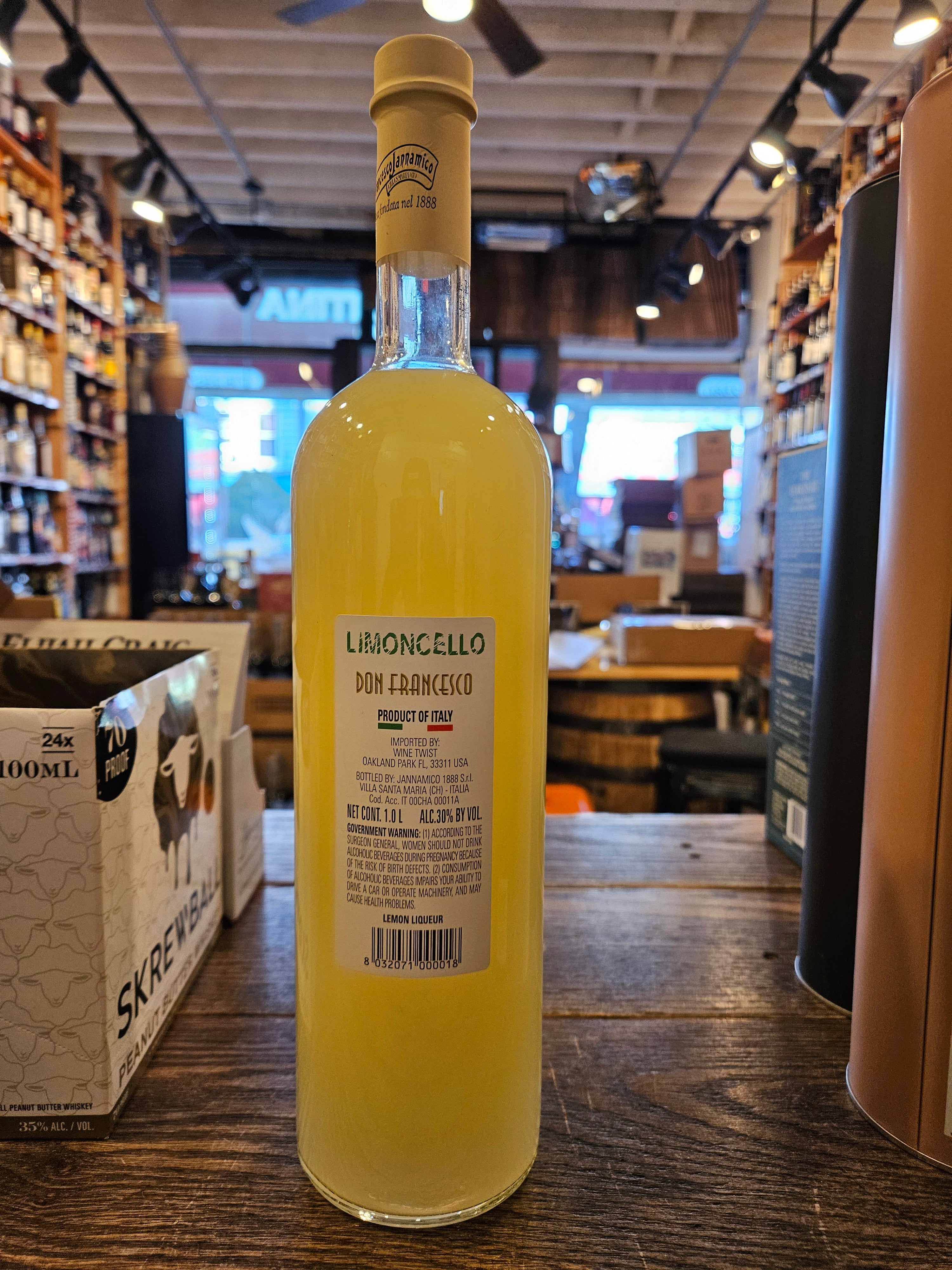 Jannamico Limoncello Don Francesco 1L the backside of a tall clear glass bottle with yellow liquid and a white label and beige top