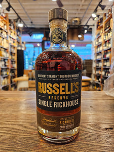 Russell's Reserve Single Rickhouse 750mL a short squat rounded shoulder clear glass bottle with a blue label and a wooden top