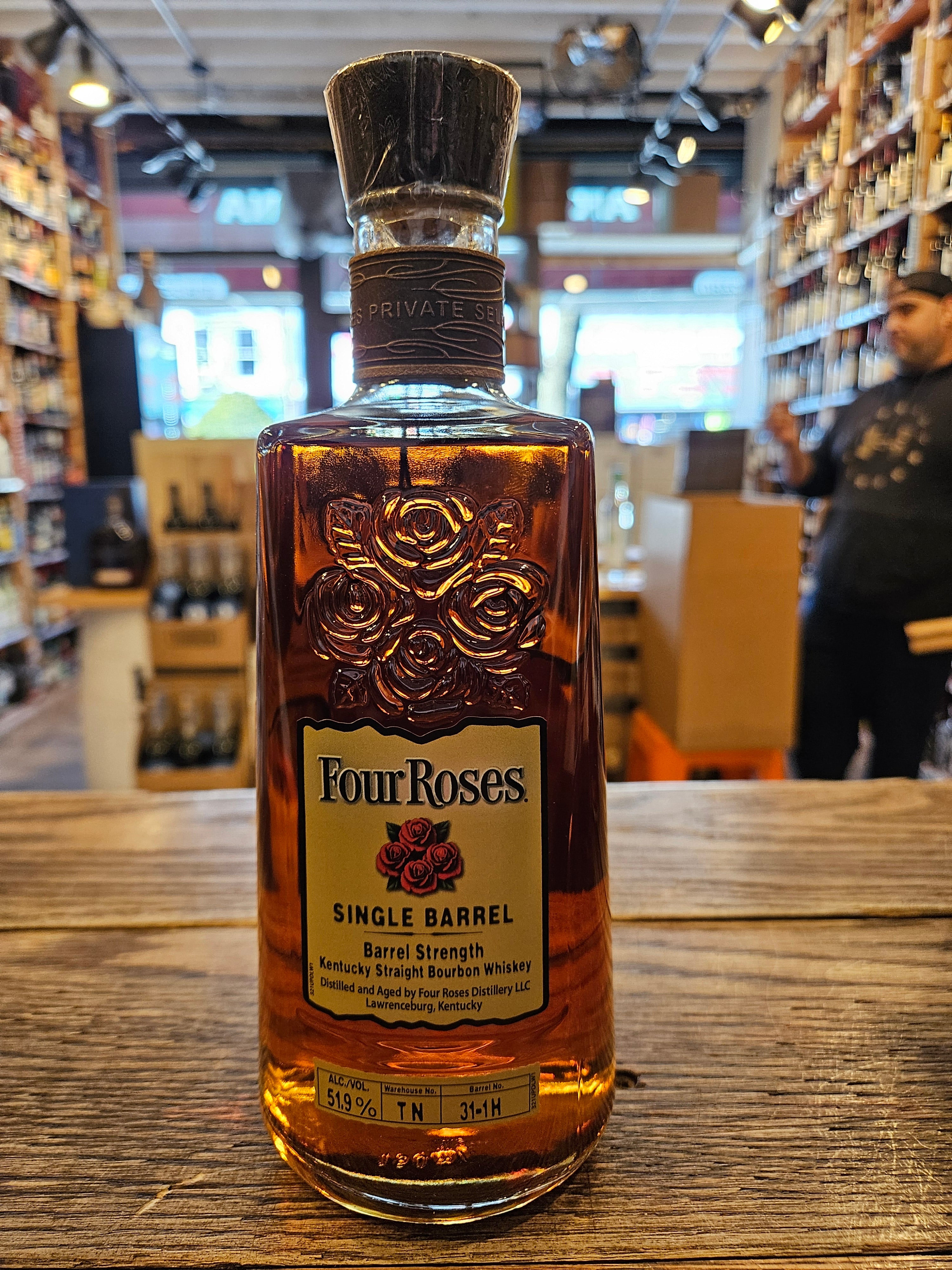 Four Roses Private Barrel Selection Barrel Strength OBSV 51.9% a clear square rounded bottle with four roses engraved on the glass with a yellow label with a leather necker and wooden top