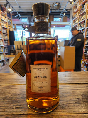 Four Roses Private Barrel Selection Barrel Strength OBSV 51.9% the backside of a clear square rounded bottle with four roses engraved on the glass with a yellow label with a leather necker and wooden top