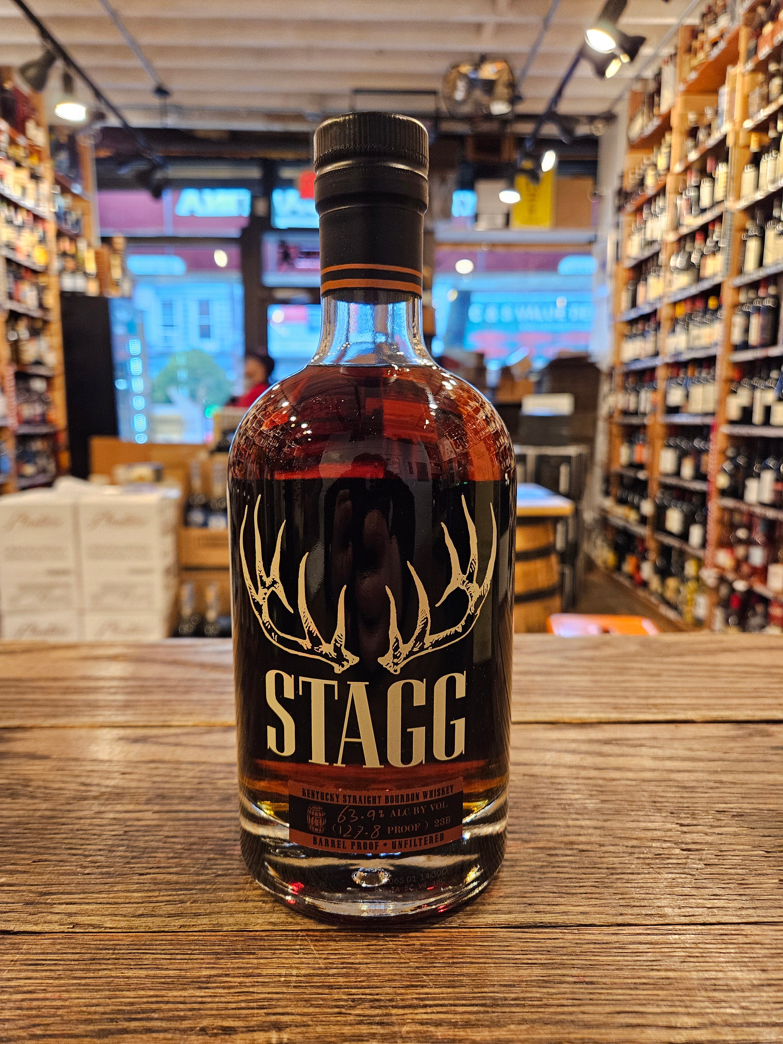 Stagg 750mL a short squat round shouldered clear glass bottle with beige lettering and the image of deer antlers on the front, with a black top.