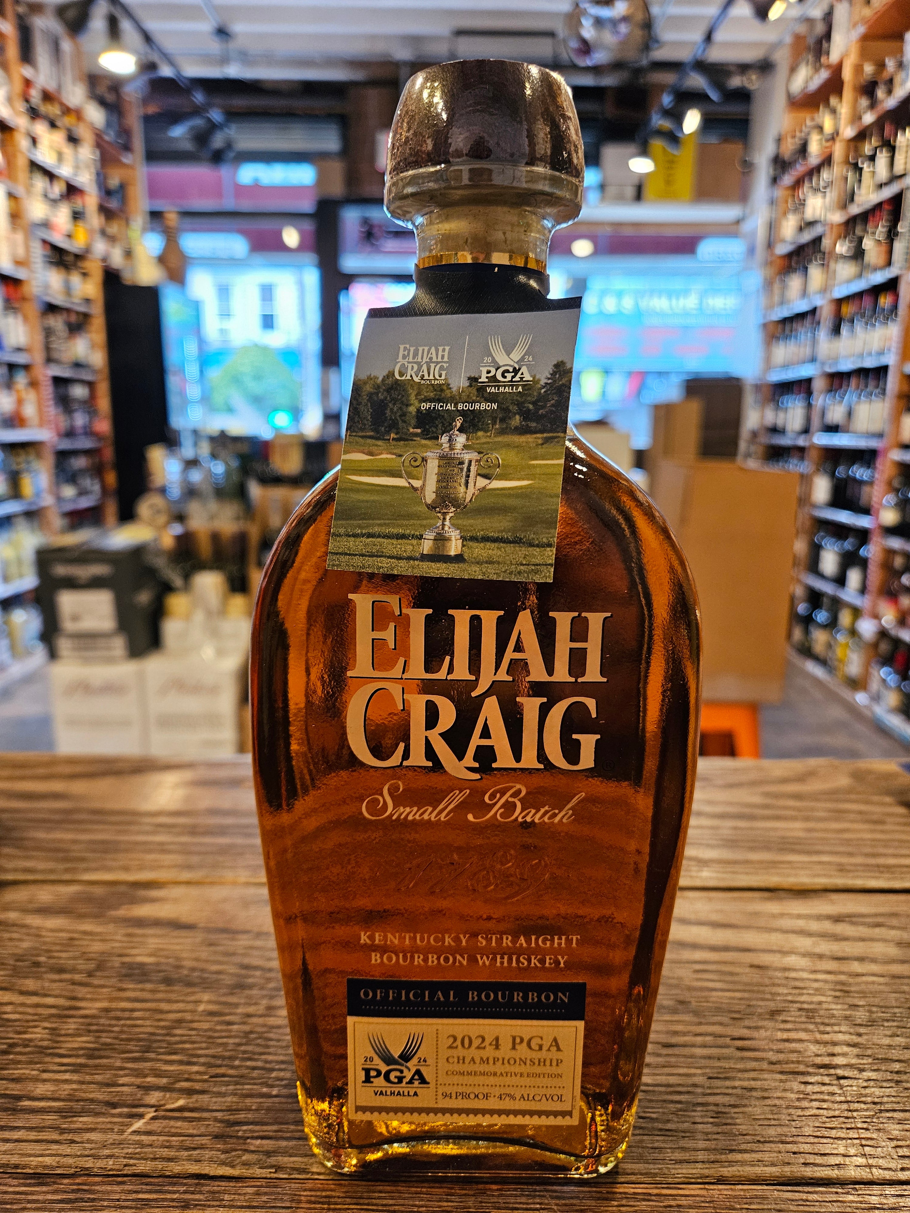 Elijah Craig Small Batch 2024 PGA Championship 750mL a clear glass short round shouldered bottle with gold lettering and a beige label at the bottom and a wooden top
