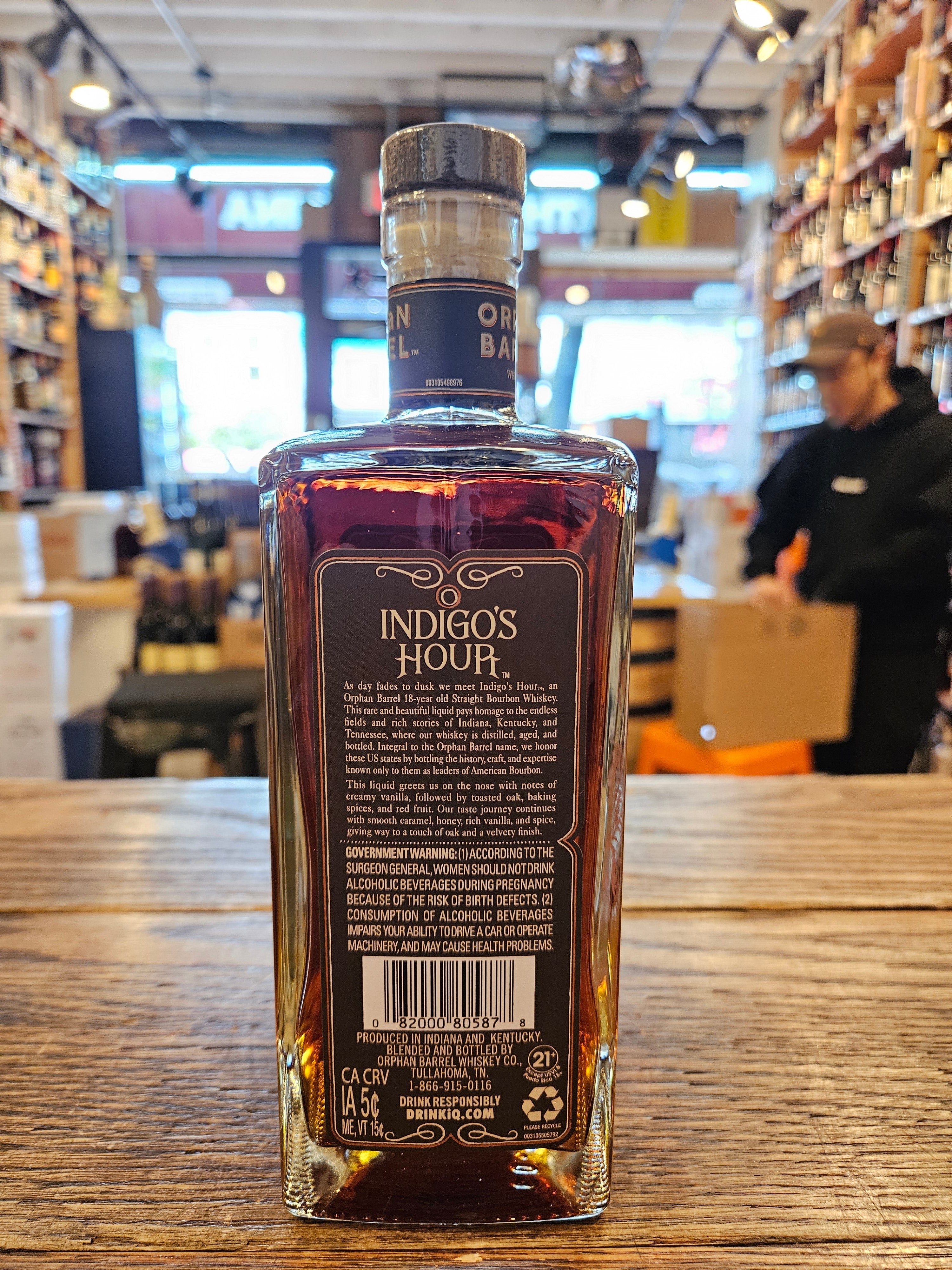 Orphan Barrel Indigo's Hour 750mL the side of a squared short clear glass bottle with a black label and a wooden top