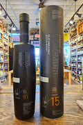 Octomore 15.1 700mL a slender frosted black glass bottle with a long neck next to a tall black cylinder. 