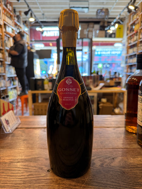 Tall clear bottle with red label and gold foil